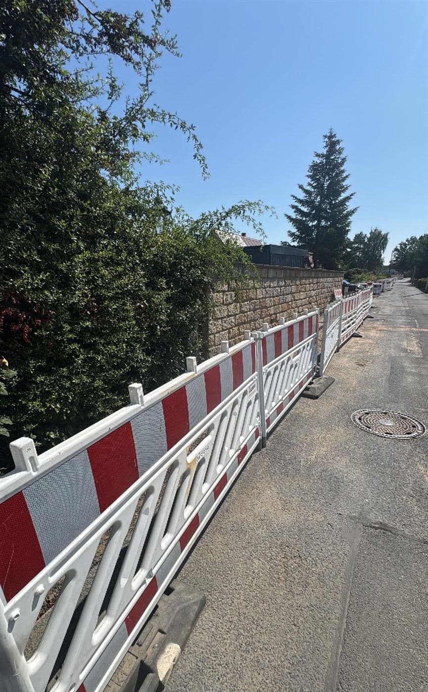 Lange Reihe rot-weißer Absperrschranken entlang einer Grundstücksmauer an der Kötitzer Straße in Dresden