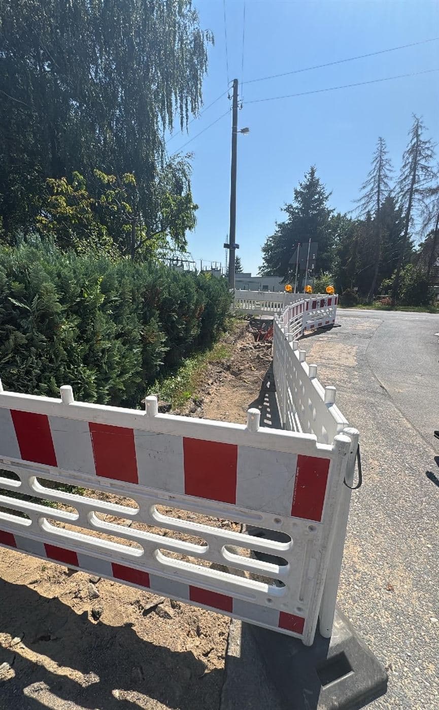 Abgesicherter Leitungsgraben für Glasfaser im Seitenstreifen der Kötitzer Straße mit Absperrschranken und Warnleuchten